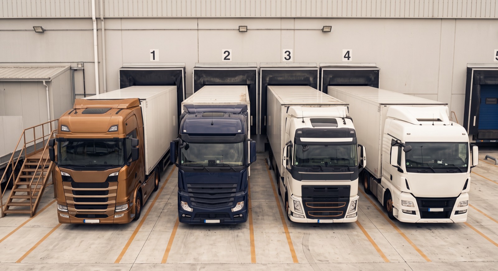 Vier Lkw an nummerierten Laderampen eines Distributionszentrums